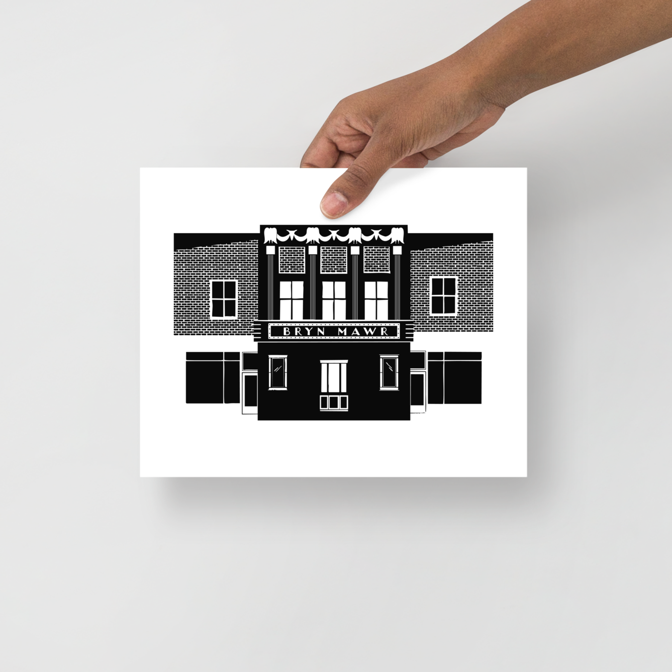 Hand holding a black and white architectural illustration on a light gray background